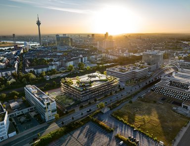 Zwischen dem pulsierenden Medienhafen und dem charmanten Lorettoviertel gelegen, bietet 5YN3RGY  Gastronomie im Erdgeschoss, Veranstaltungsflächen und einen großzügigen Innenhof. Es wird vollständig klimaneutral betrieben durch Geothermie, Photovoltaik und effiziente Luftspülung. - © Moka Studio